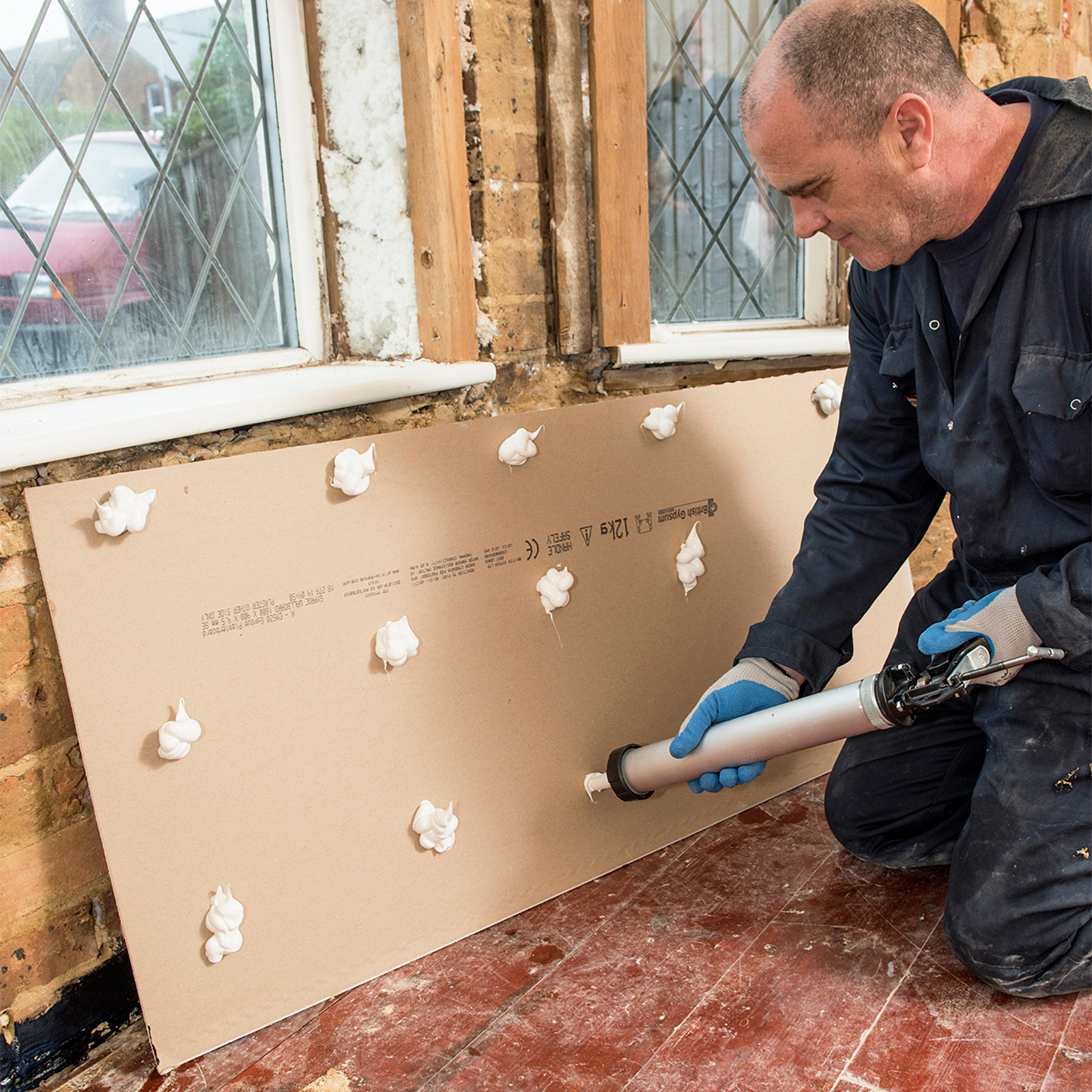 Tragen Sie Drygrip Klebstoff auf der Rückseite der Gipsplatte auf